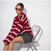 Woman wearing a red and white striped sweater sitting on a chair against a white background